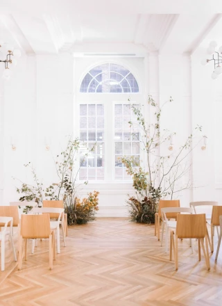 A bright and airy lobby with white walls, wooden floors, and a large window.