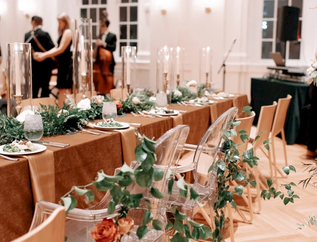 A long table set for a formal event with candles, greenery, and flowers.