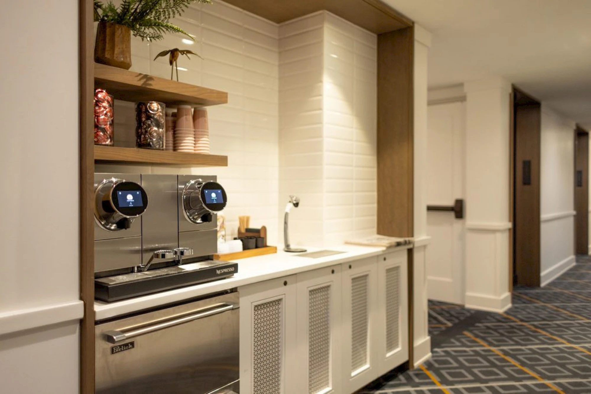 A kitchenette with a coffee maker, sink, and dishwasher.