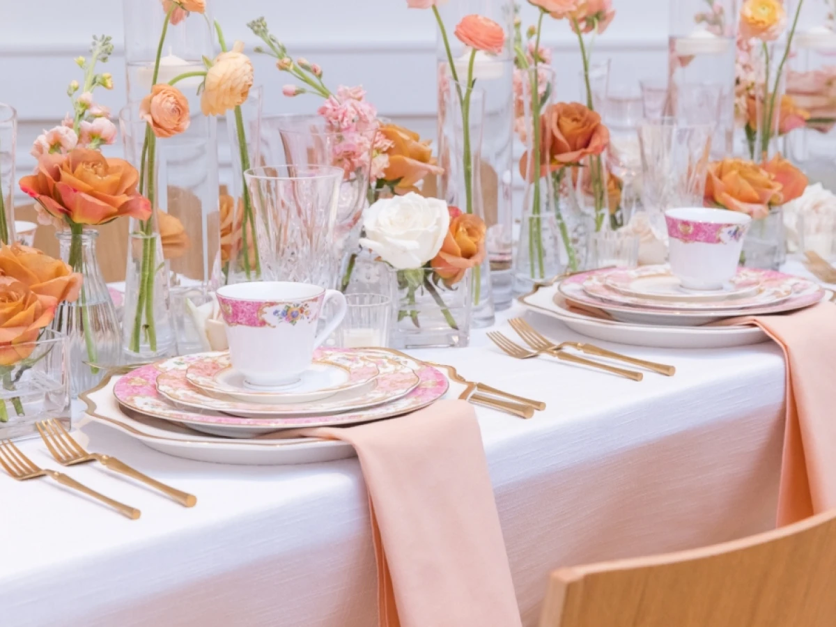 a formal dining table set with flowers and goldware