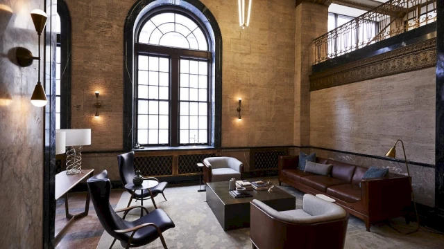 A spacious lobby with a large window, leather sofa and chairs, and a coffee table.