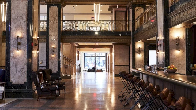 A wide view of a hotel lobby with a bar, seating area, and staircase.