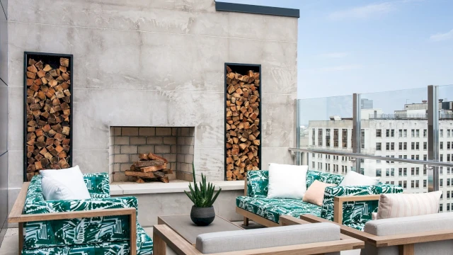 A rooftop patio with a fireplace and outdoor seating area overlooking the city.