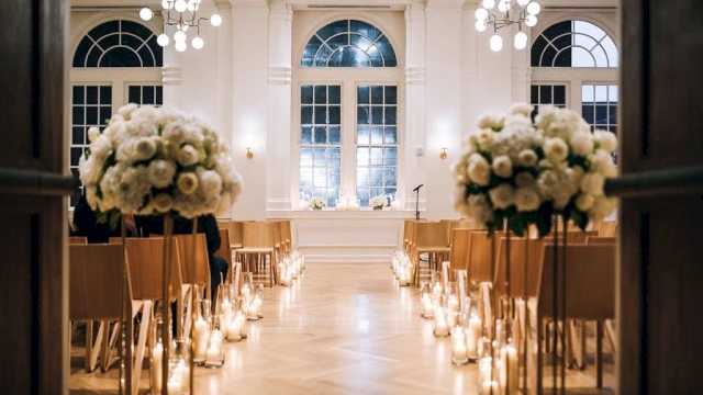 A brightly lit event space with white flowers, candles, and chairs set up for an event.