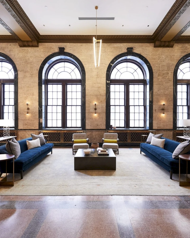 A spacious lobby with a seating area, large arched windows, and modern lighting.