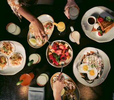 A table with various dishes and glasses, with two people's hands visible