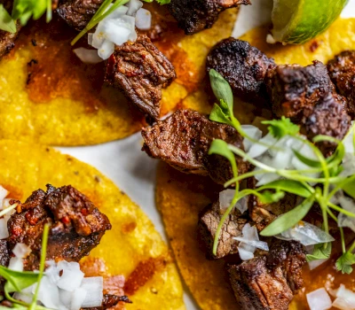 A close-up view of tacos with meat, onions, and herbs.
