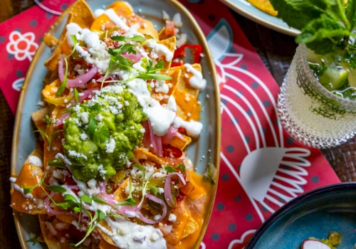 A plate of nachos with cheese, guacamole, and sour cream.