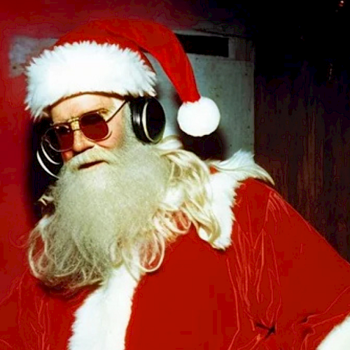 Santa Claus is wearing sunglasses and headphones, standing in front of a festive background with Christmas lights and decorations.