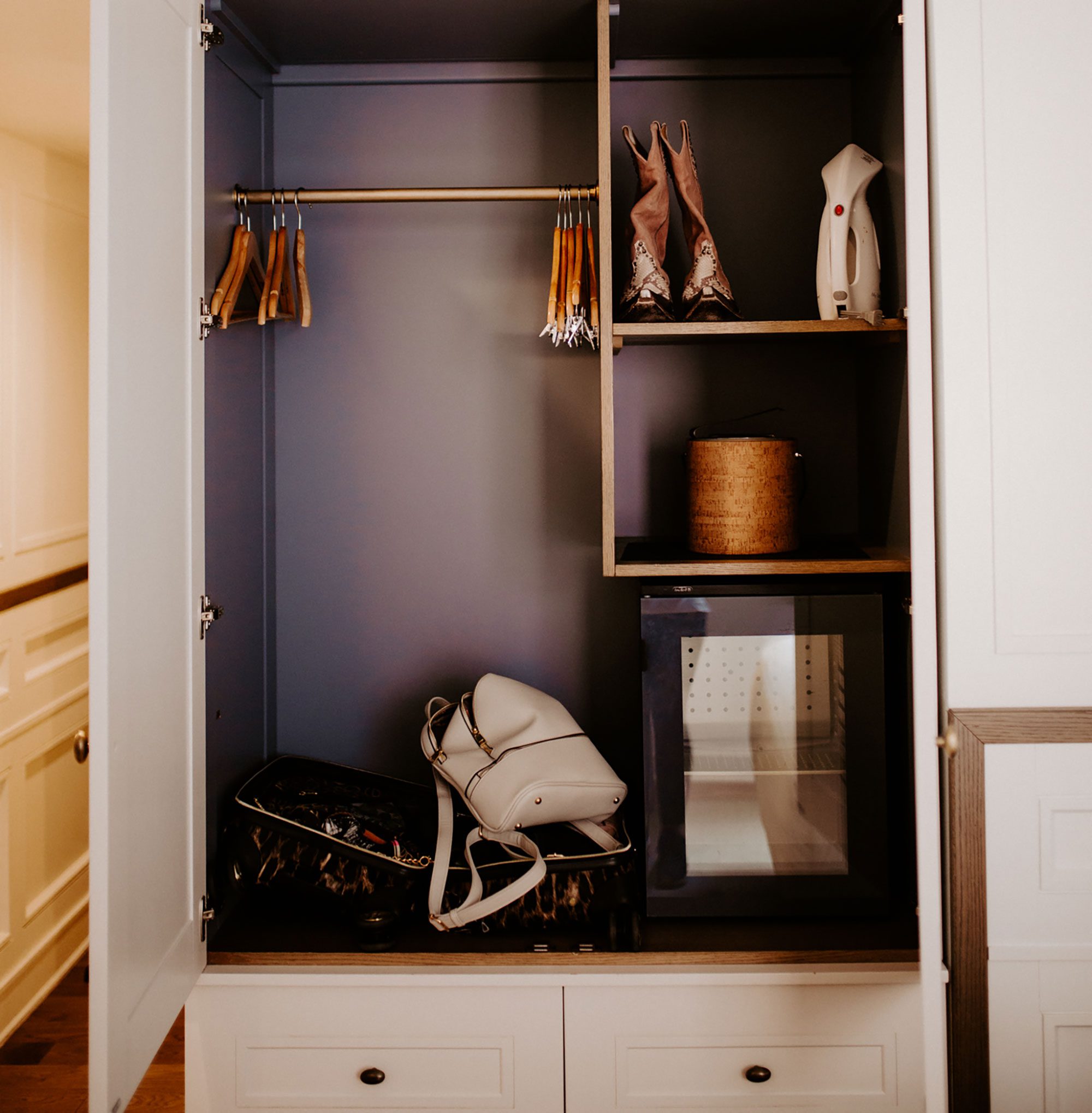 A closet with a hanging rod, shelves, drawers, and a mini fridge.
