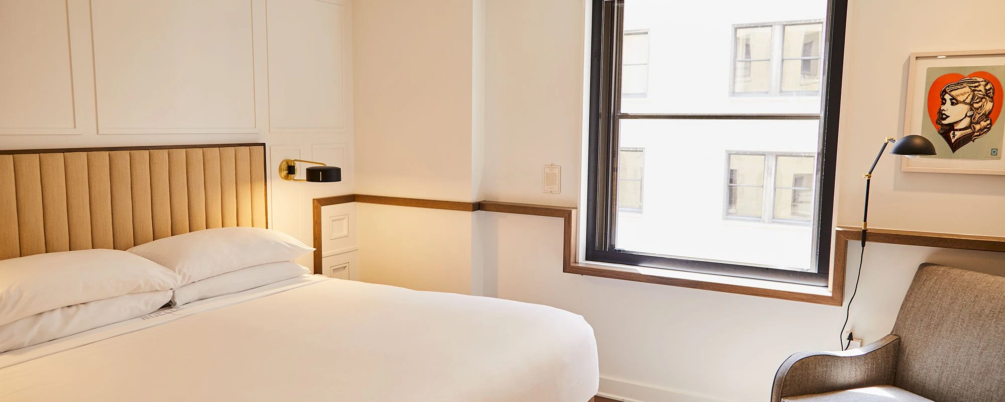 A hotel room with a bed, chair, and window