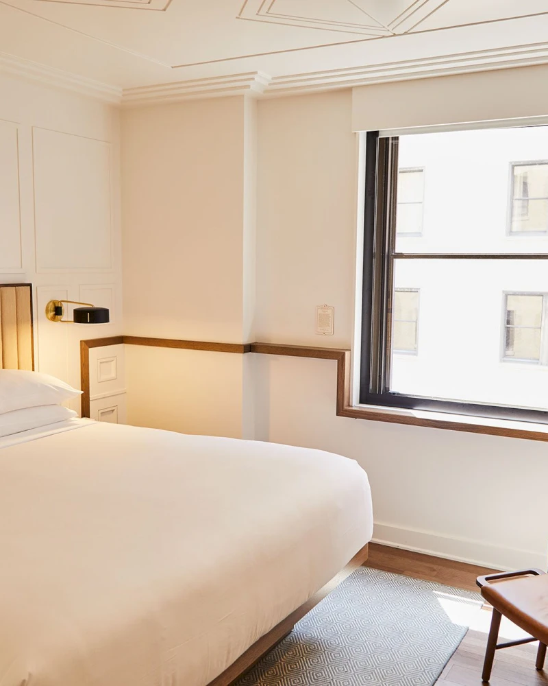 A hotel room with a bed, window, and chair
