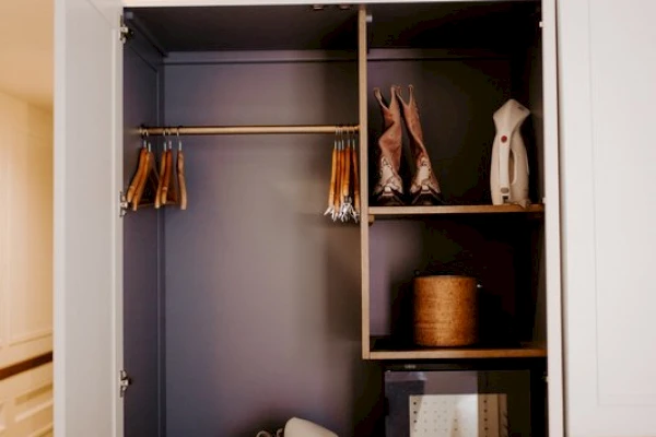 A closet with a clothing rod and shelves containing clothing and accessories.