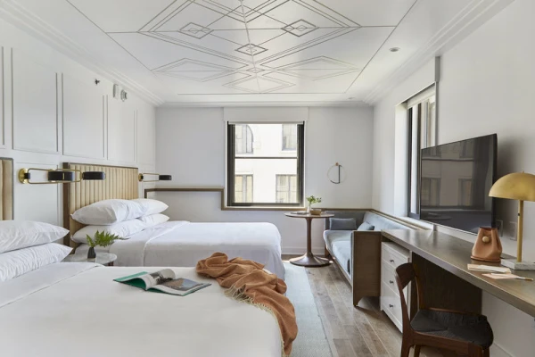 A hotel room with two beds, a desk, and a window
