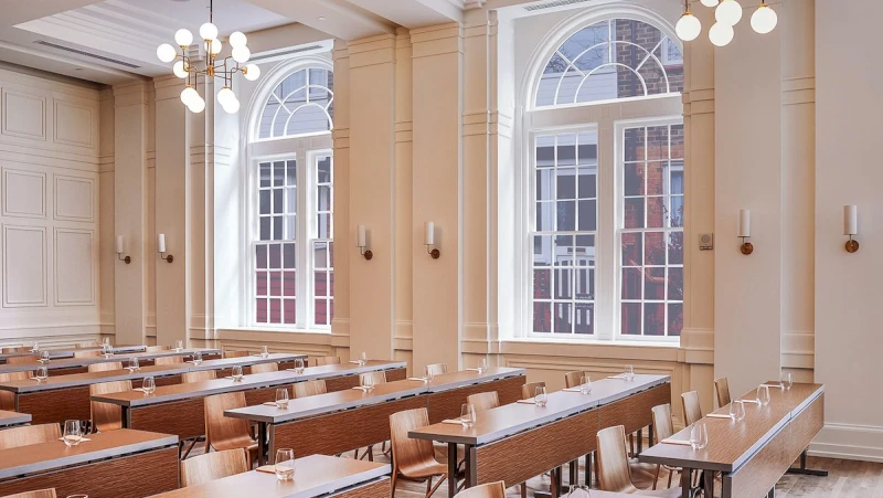 A large meeting room with tables, chairs, and windows.
