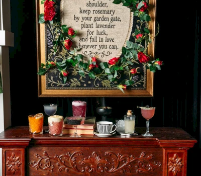 a selection of colorful drinks on a wooden bar with a framed piece of art in the background