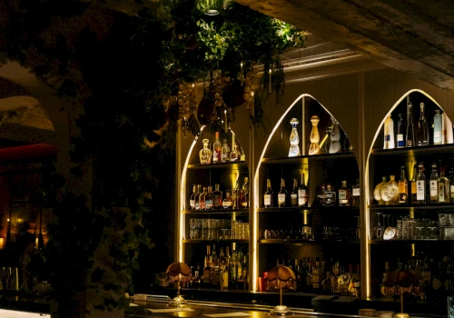 a dimly lit bar with arched shelving full of liquor bottles
