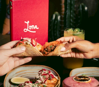 A taco and a drink on a table with a menu